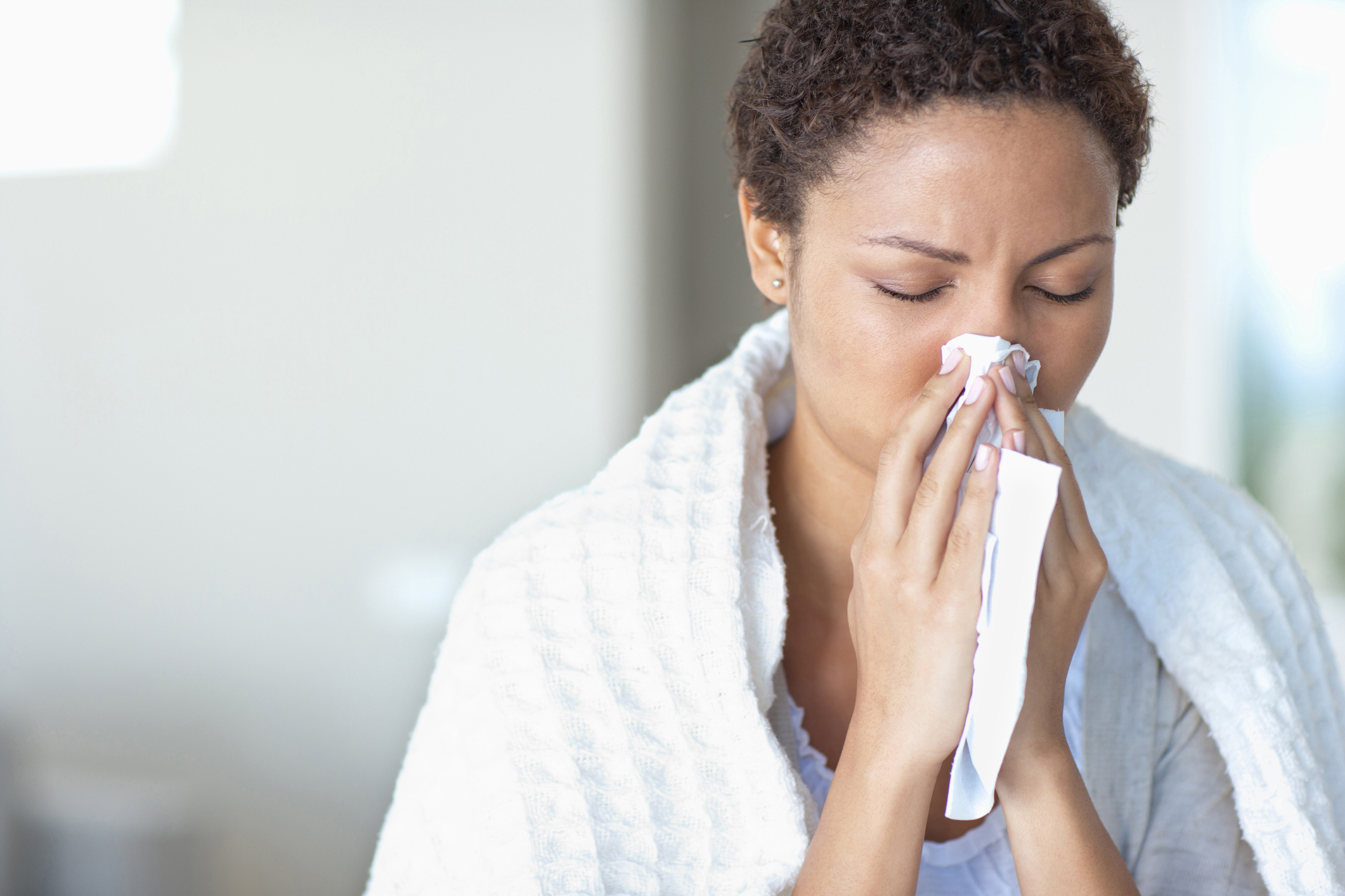 Young woman blowing her nose. Jamaica's on flu alert, here's how to avoid getting sick. 