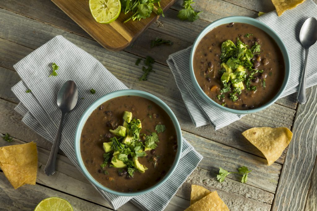 Black bean soup topped with pieces of avocado. 