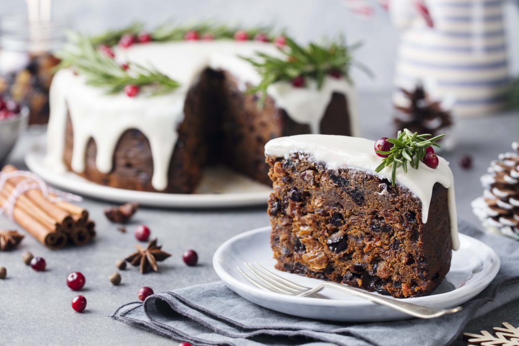 Findyello article on Caribbean Christmas recipes with image showing a sliced of fruit cake with icing and holly garnish.
