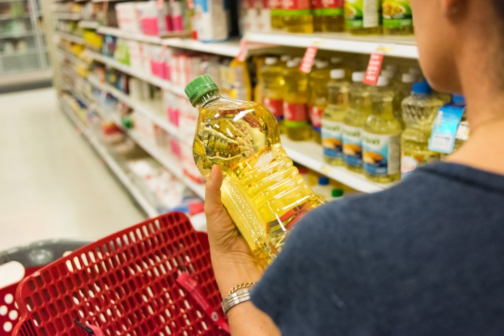 Findyello article on best cooking oils image shows woman shopping for cooking oil in the supermarket