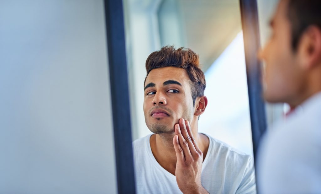 Findyello article Caribbean Man how to treat razor bumps with image showing man looking at face