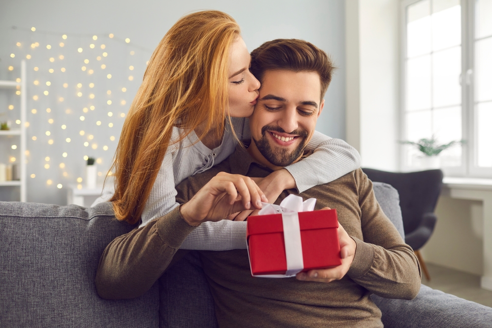 Findyello Valentine's day article with tips for presents for men showing image of smiling couple with man opening present.