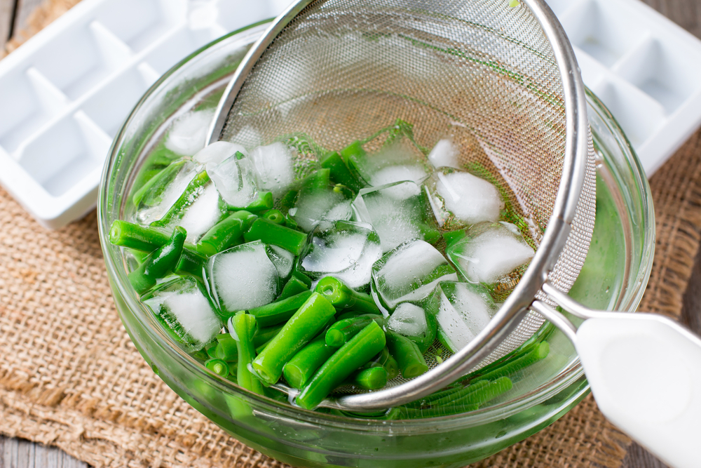 Findyello article with tips to have your fresh produce last longer with image of beans in bowl with blocks of ice.