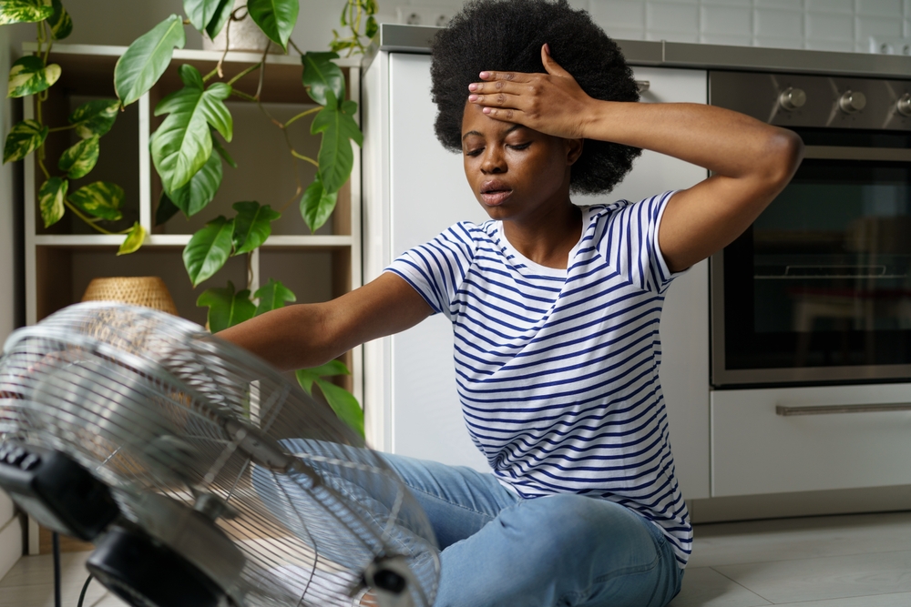 Findyello article sharing tips to beat the heat with image of woman sitting in front of a fan